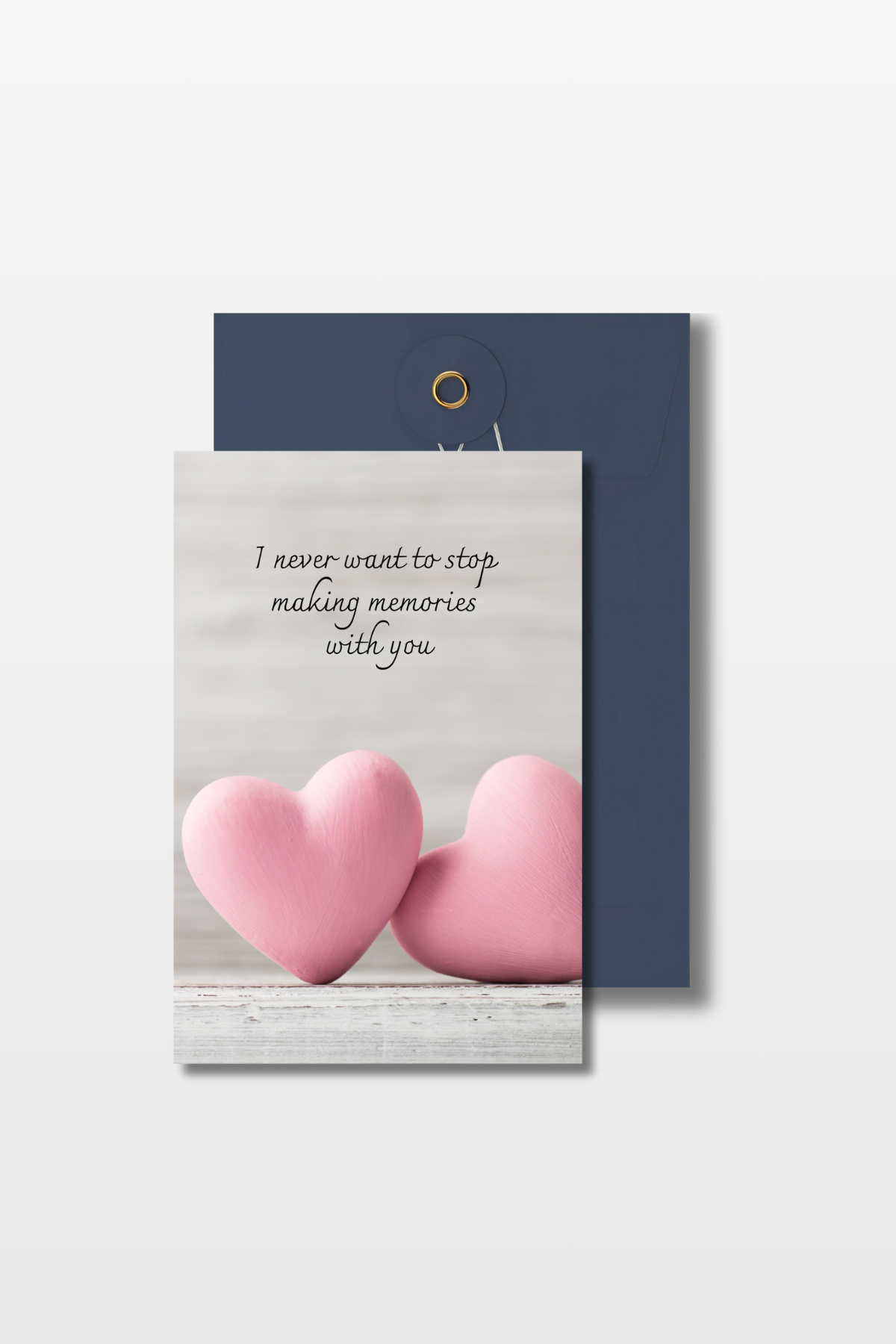 Liefdeskaart met de tekst 'I never want to stop making memories with you' en twee roze harten op een grijze achtergrond met een blauwe envelop