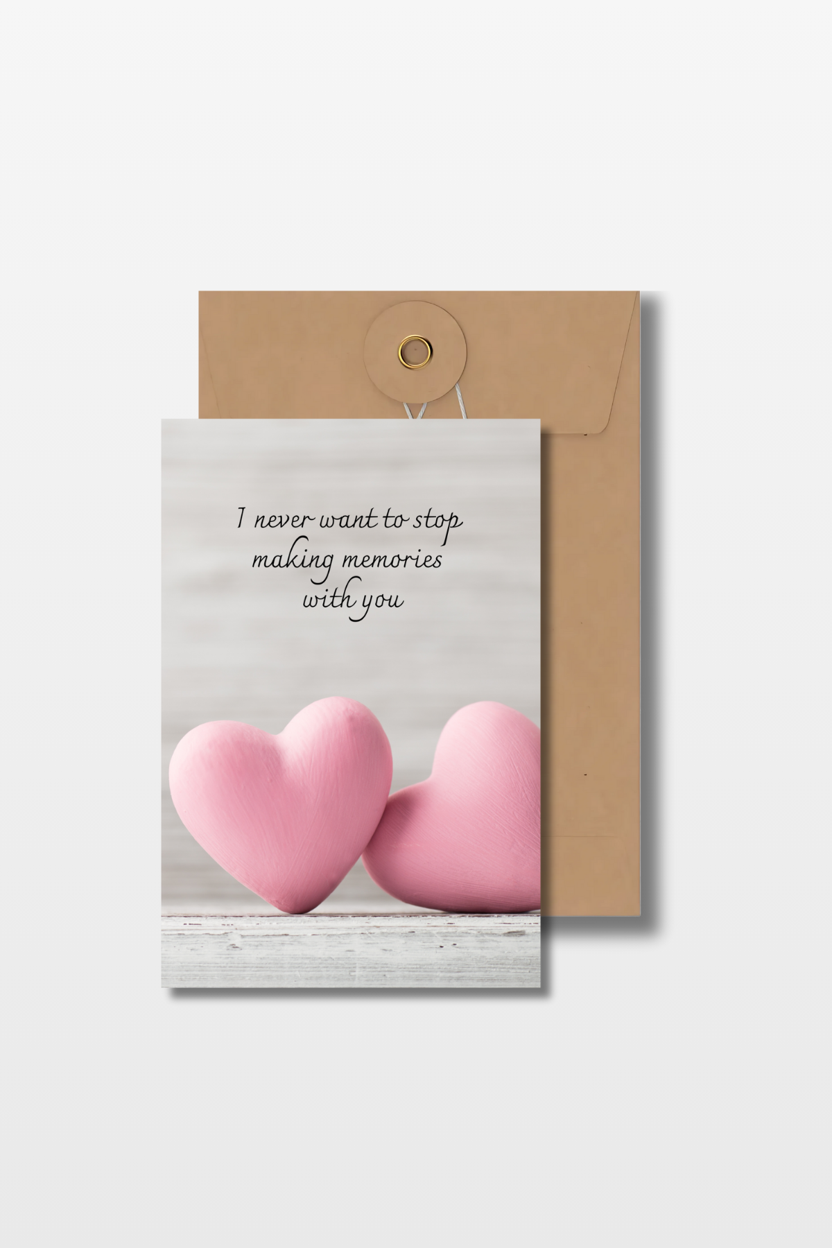 Liefdeskaart met de tekst 'I never want to stop making memories with you' en twee roze harten op een grijze achtergrond met een bruine envelop