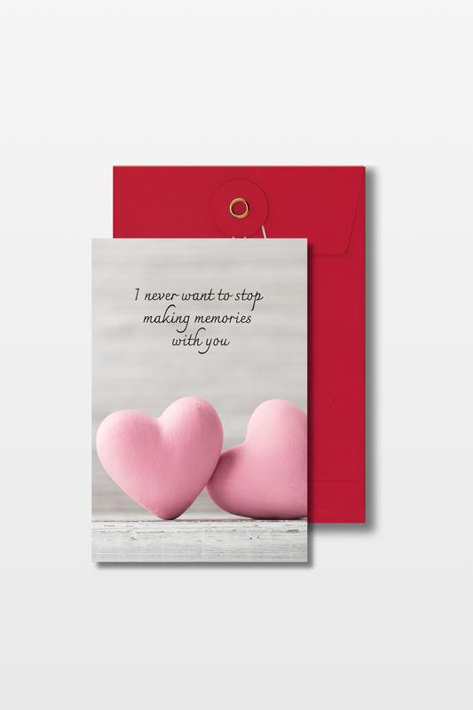 Liefdeskaart met de tekst 'I never want to stop making memories with you' en twee roze harten op een grijze achtergrond met een rode envelop
